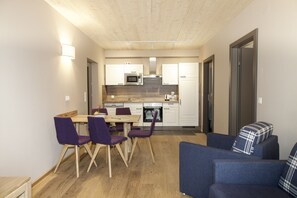 A compact living space with a dining area, kitchenette, and a sofa.