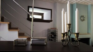 A staircase with a modern design, a framed picture on the wall, and a table with candles and a book. - Tsarbou Guesthouse (Gortynia)