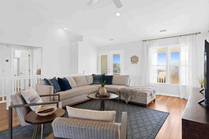Una sala de estar moderna con un sofá modular, una mesa de centro redonda y un mueble para televisión.