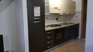 A compact kitchen with a refrigerator, stove, sink, and dishwasher.