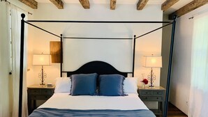 Una cama con dosel, un cabecero oscuro, dos mesitas de noche con lámparas y techo de madera.