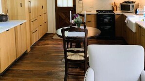 Una cocina compacta con armarios de madera, una mesa de comedor con sillas y un sofá.