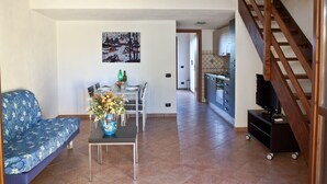 A living room with a sofa, dining table, and a TV on a stand.