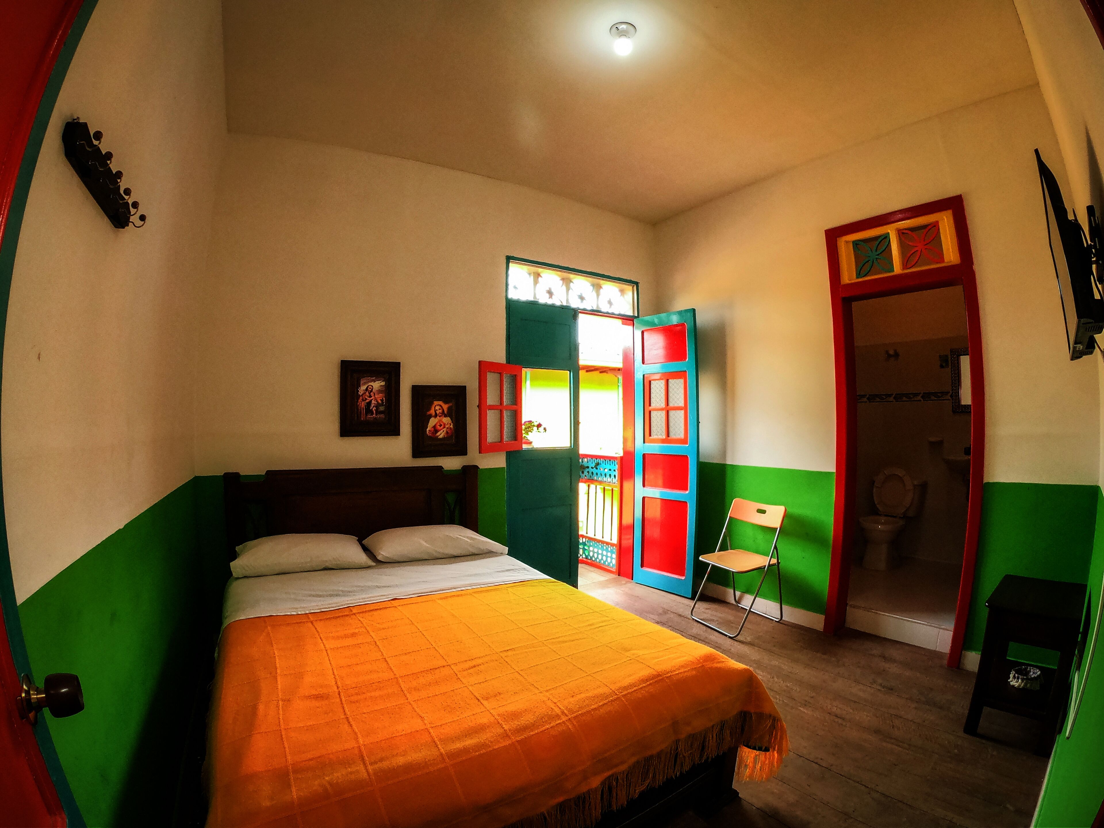Una camera da letto con un letto, una sedia e una porta che dà su un bagno.