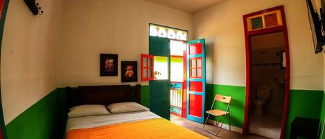 A bedroom with a bed, a chair, and a door leading to a bathroom.
