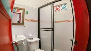 A bathroom with a toilet, sink, and shower area.