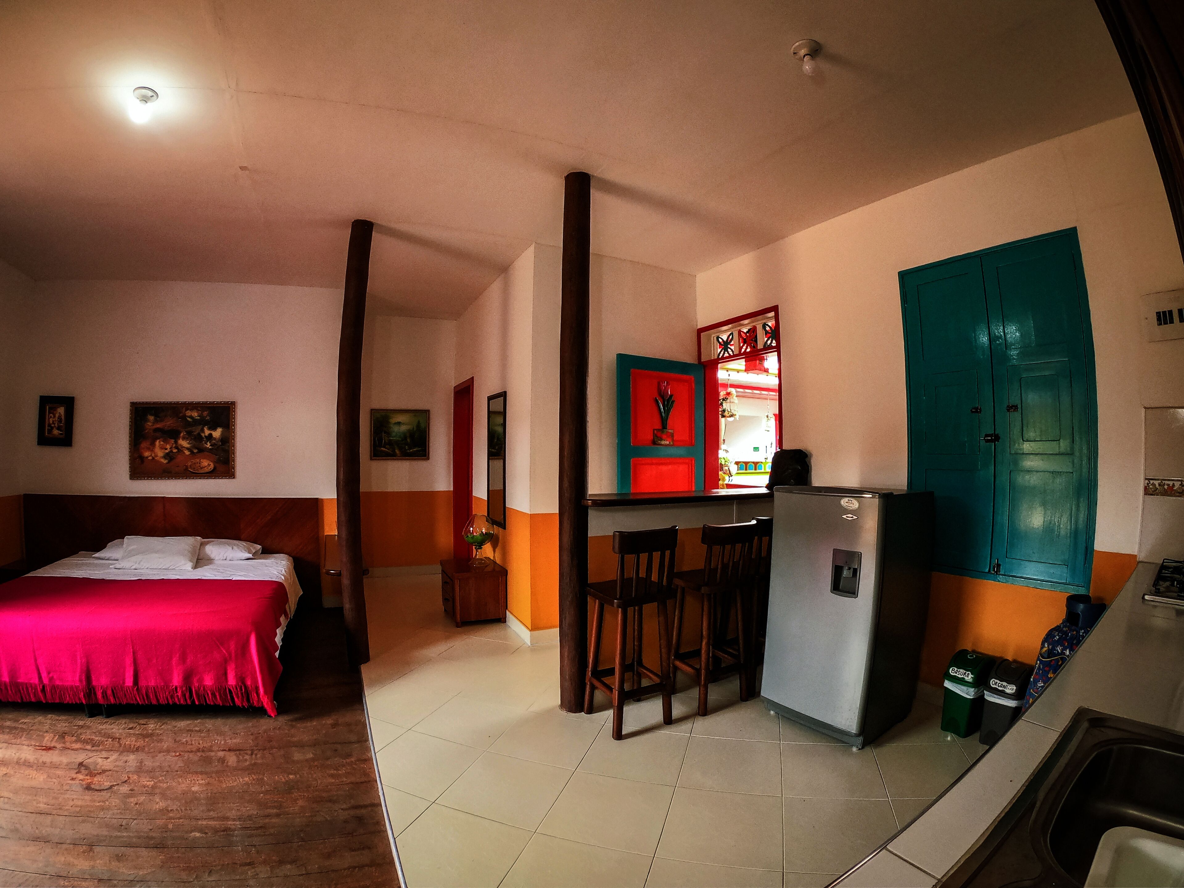 A room with a bed, a small kitchen area with a refrigerator, and a dining area with chairs.