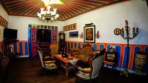 Una habitación con una lámpara de techo en forma de estrella, un televisor, un sofá, sillas, un reloj y un candelabro.