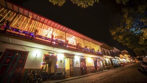 Un edificio con un balcón decorado con luces y un letrero que dice 
