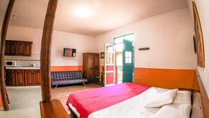 Una habitación con cama, sofá, televisión y kitchenette.