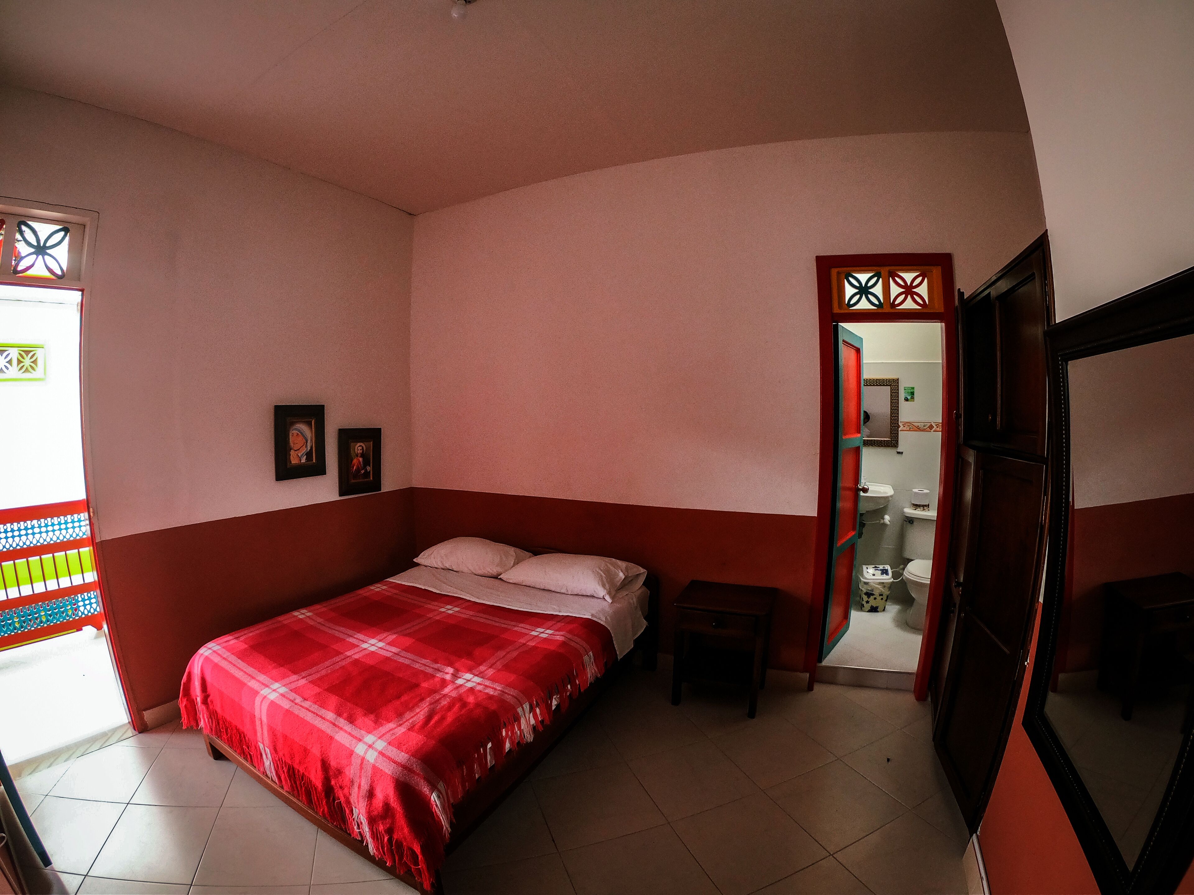 A bedroom with a bed, a small bedside table, and a door leading to a bathroom.