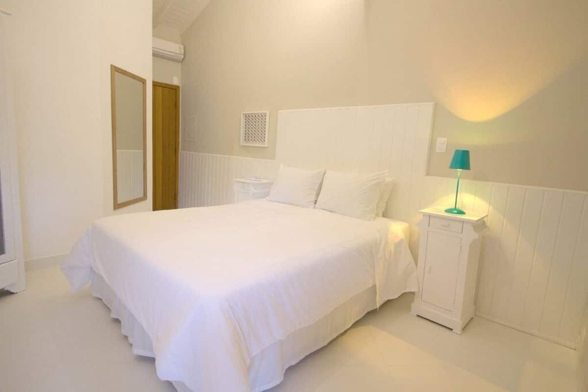 A bedroom with a large bed, a nightstand, a lamp, and a mirror.