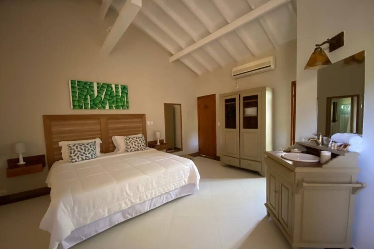 A bedroom with a large bed, a wardrobe, a vanity with a mirror, and a ceiling fan.