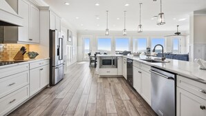 Una cocina moderna con gabinetes blancos, electrodomésticos de acero inoxidable y una isla grande con pileta.