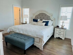 Un dormitorio con una cama grande, una mesita de noche, una lámpara y un banco.