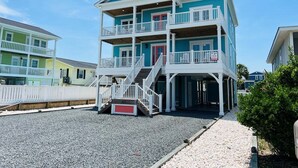 Un edificio a più piani affacciato sulla spiaggia, con balconi e una scala.