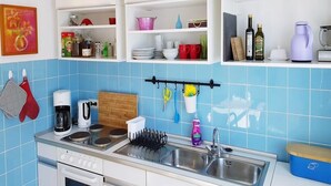 A kitchen with white cabinets, a blue tiled backsplash, a stove, a sink, and various kitchen utensils and appliances. - Large roof terrace - Sun-drenched apartment - Elevator available (Bremerhaven)