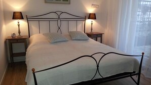 A neatly made bed with a metal frame, two bedside tables with lamps, and a window with sheer curtains. - Large roof terrace - Sun-drenched apartment - Elevator available (Bremerhaven)