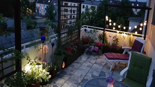 A rooftop patio with a seating area, string lights, and potted plants. - Large roof terrace - Sun-drenched apartment - Elevator available (Bremerhaven)
