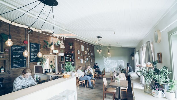Interior de restaurante con paredes de madera, lámparas colgantes y un menú en la pizarra.