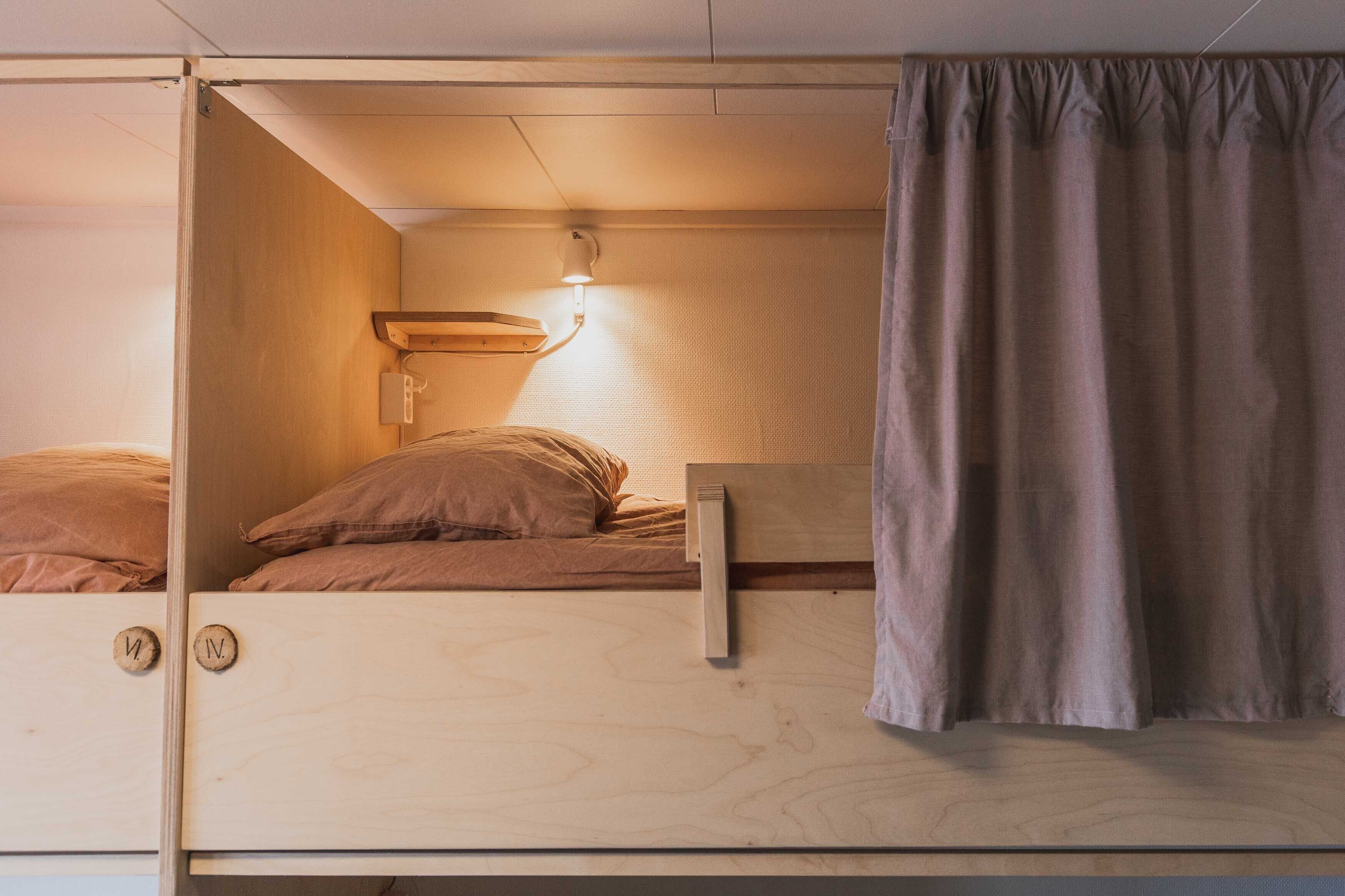 A bunk bed with a headboard, a bedside lamp, and a curtain.