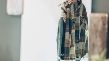 A plaid shirt hanging on a line in a room with a rustic decor, including a wooden beam and a whiteboard.