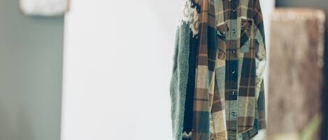 A plaid shirt hanging on a line in a room with a rustic decor, including a wooden beam and a whiteboard.