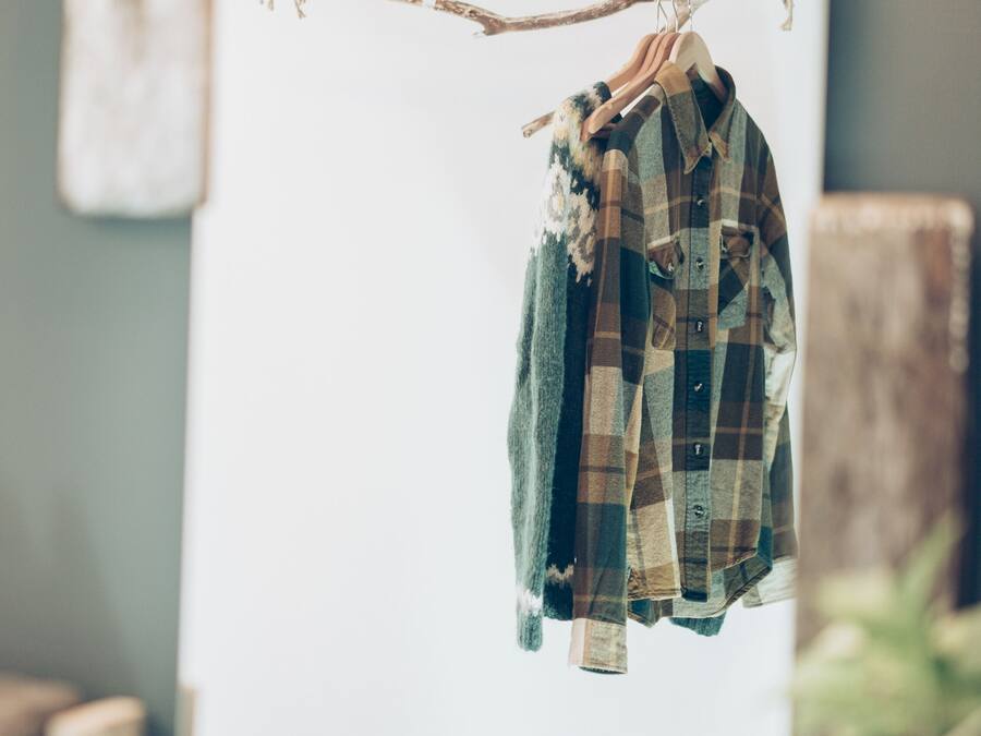 A plaid shirt hanging on a line in a room with a rustic decor, including a wooden beam and a whiteboard.