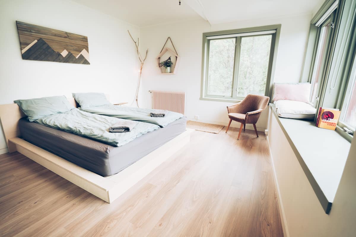 A modern bedroom with a bed, a chair, a window, and a radiator.