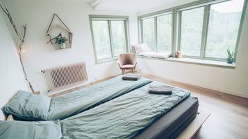 A bedroom with a bed, a chair, a window, and a radiator.