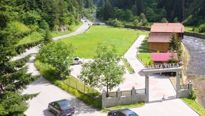 A mountain lodge with a paved driveway, a parking area, and a view of the surrounding forest and mountains. -  Raha Villa Bungalow (Çaykara)
