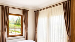 A bedroom with a large bed, a window with curtains, and a ceiling light.