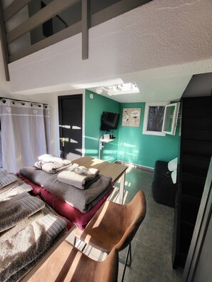 Une chambre avec un lit, une table avec des serviettes, une télévision et une chaise.