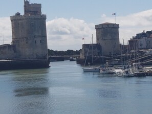 A historic stone castle with two towers, a calm harbor with boats, and a clear sky. - 40 m² apartment with a pool in a residential complex offering a beautiful view of the Minimes Harbor (La Rochelle)