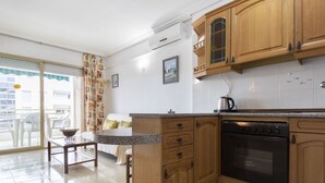 Une cuisine avec des meubles de rangement en bois, un four encastré et un coin repas comprenant une table et des chaises.