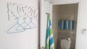 Une salle de bain avec des toilettes, un porte-serviettes avec des serviettes à rayures et un élément décoratif mural.