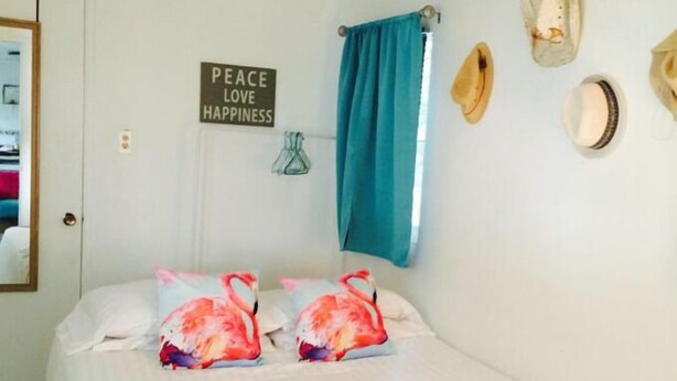 Une chambre à coucher avec un lit, un panneau sur le mur et une fenêtre avec des rideaux.