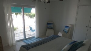 Un dormitorio con cama, una silla, un armario y vistas al exterior.