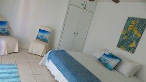 Un dormitorio con cama, una silla, un armario y un cuadro en la pared.