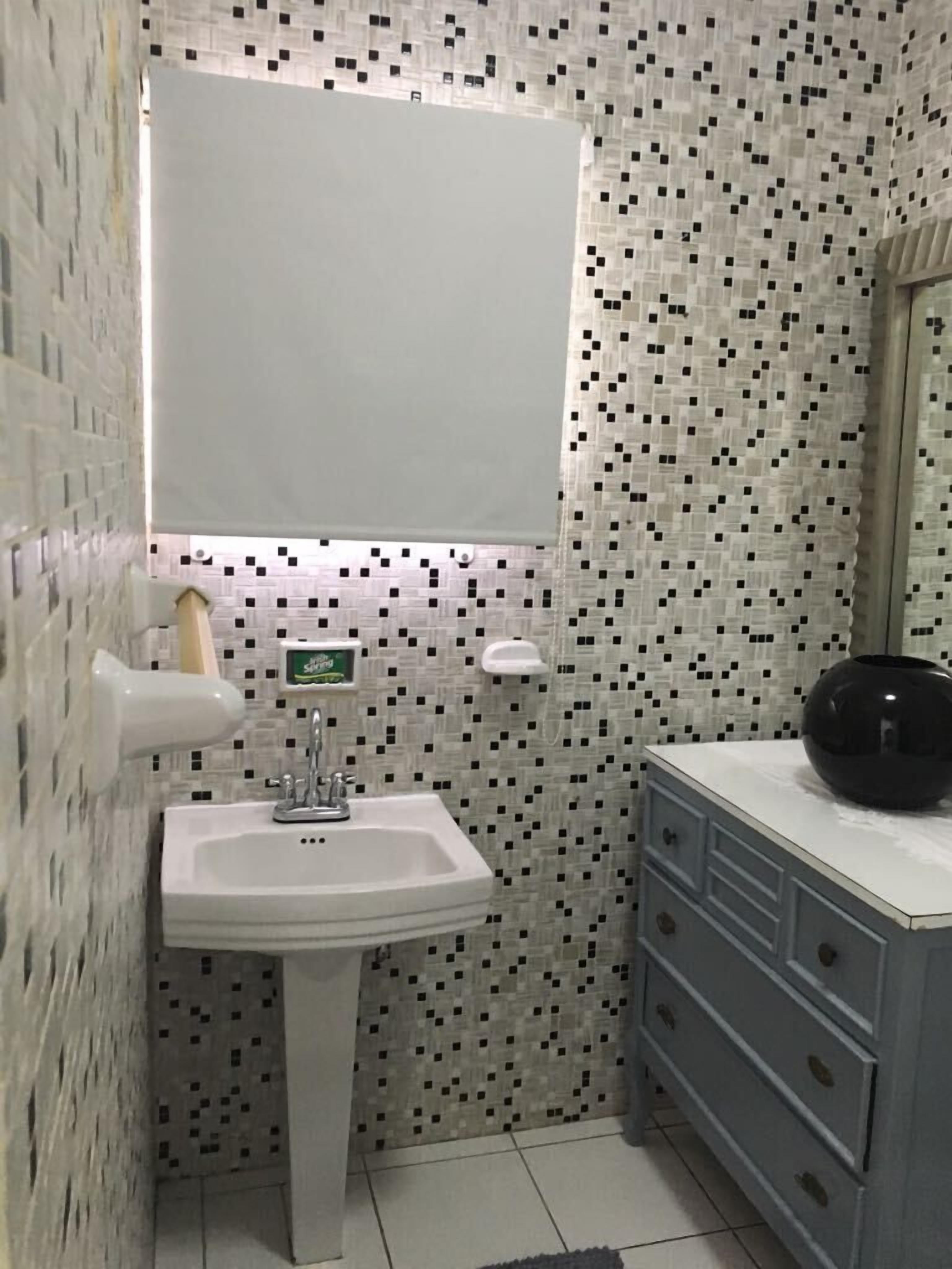 A bathroom with a white sink, a mirror, and a tiled wall.