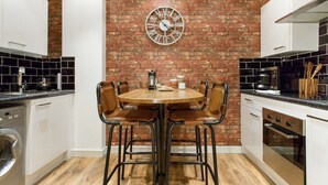 Una cocina con pared de ladrillo, una mesa redonda con cuatro sillas y electrodomésticos modernos.