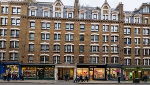 A multi-story building with a classic architectural style, featuring a row of arched windows and a central entrance.