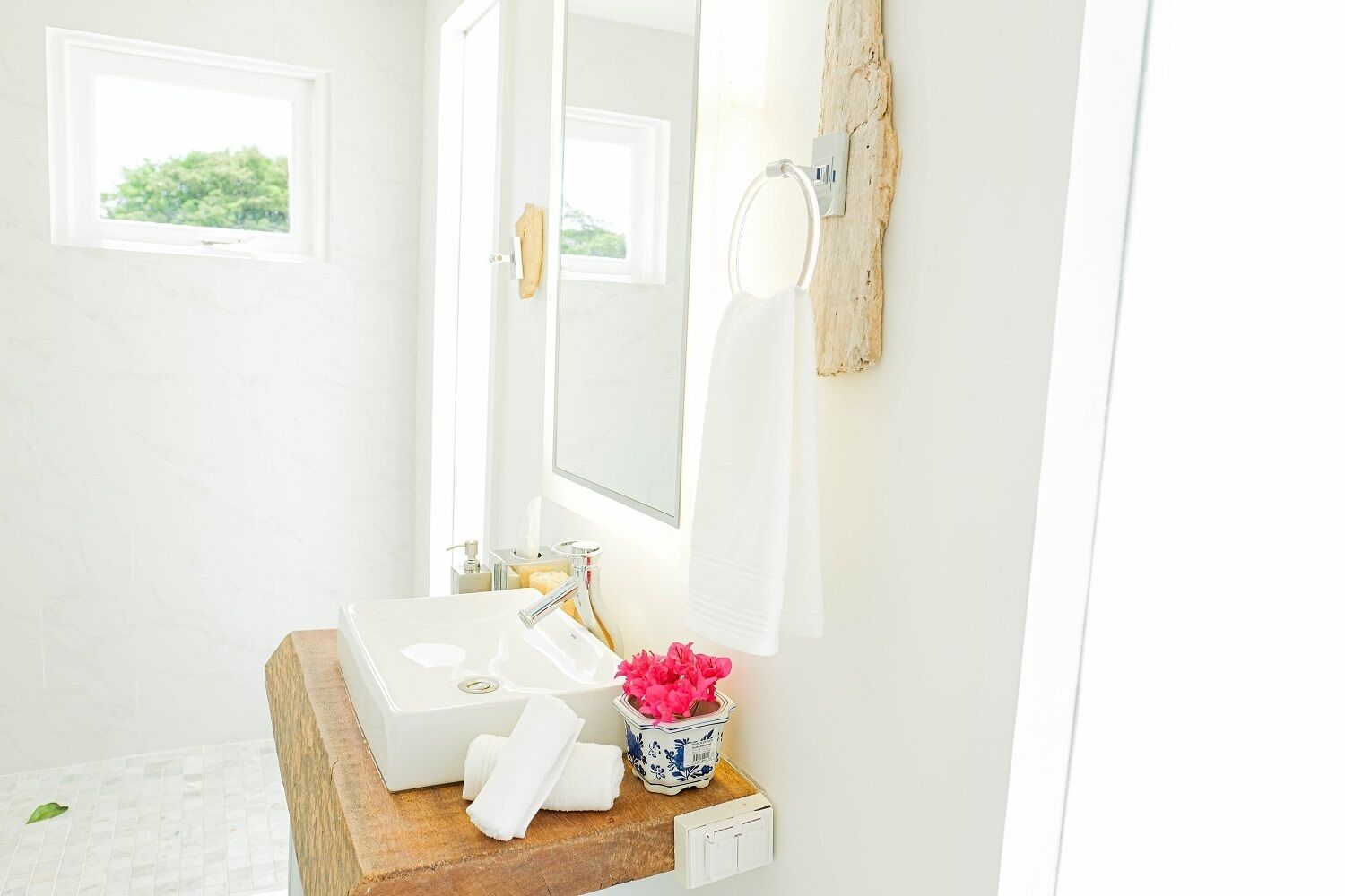A bathroom with a white sink, a mirror, and a wooden vanity.