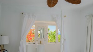 A bedroom with a large window, a white sink, and a bed with a striped pillow. - Ocean Front Property - Villa 5 Aruba Stunning (Savaneta)