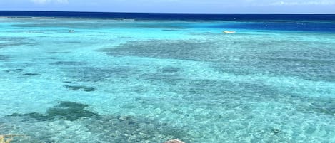 A clear view of a beach with turquoise water and a sandy foreground.