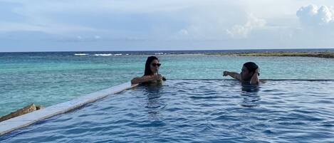A swimming pool with clear blue water and a view of the ocean.