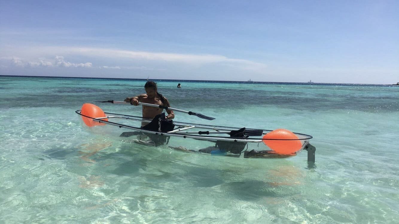 Una persona remando en aguas turquesas y transparentes.