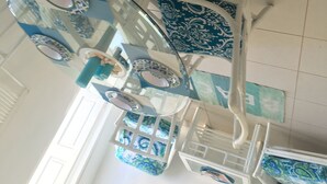 Um quarto com teto branco, paredes brancas e chão com padrão azul e branco. Há uma porta branca no lado esquerdo.