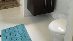 Une petite salle de bain avec un lavabo blanc, des meubles sombres, des toilettes et une petite fenêtre.