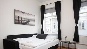 A modern bedroom with a large bed, a small bedside table, and a window with curtains. - Stunning 2BR apt with balcony view in Reykjavik (Reykjavík)